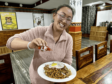 Žena kvapká tekuté chilli na rezance s vajcom